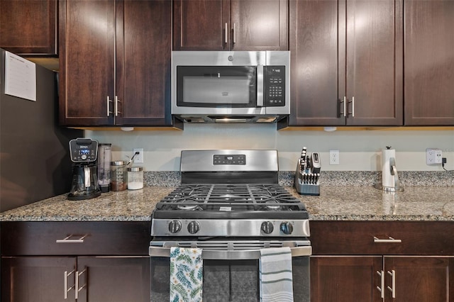 kitchen with light stone counters, stainless steel appliances, and dark brown cabinetry