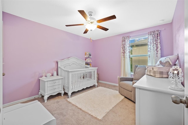 carpeted bedroom featuring a crib and ceiling fan