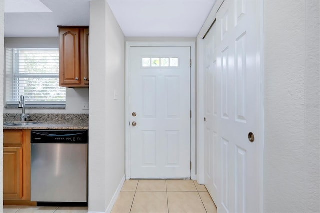 kitchen featuring stainless steel dishwasher, light tile patterned floors, and sink