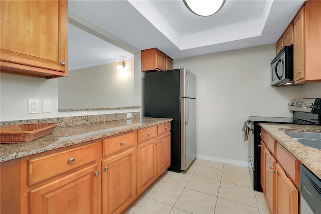 kitchen with light tile patterned flooring, stainless steel appliances, a tray ceiling, and light stone countertops