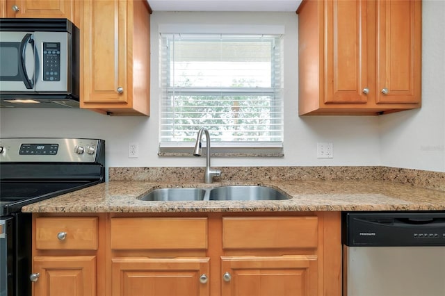 kitchen with appliances with stainless steel finishes, sink, and light stone counters