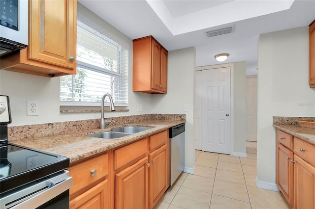 kitchen featuring light stone countertops, sink, light tile patterned floors, and stainless steel appliances