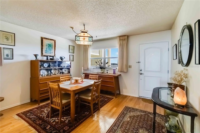 dining room with a textured ceiling and light wood-type flooring