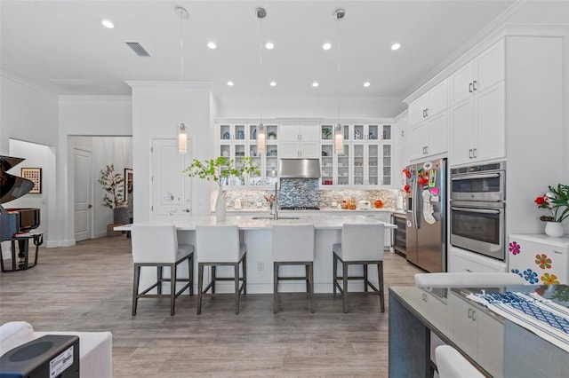 kitchen featuring pendant lighting, a kitchen bar, white cabinetry, and appliances with stainless steel finishes