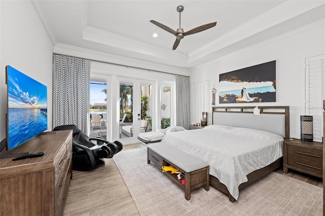 bedroom featuring crown molding, light hardwood / wood-style floors, french doors, access to outside, and a raised ceiling