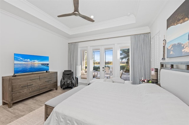 bedroom with crown molding, a tray ceiling, light wood-type flooring, and access to outside