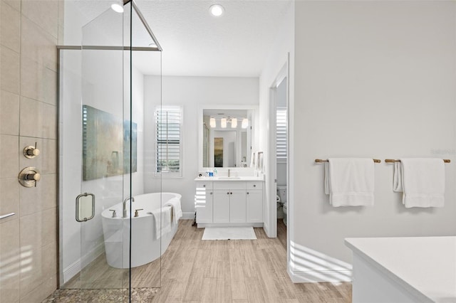 bathroom with vanity, wood-type flooring, shower with separate bathtub, and a textured ceiling