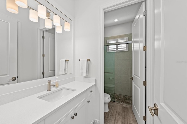 bathroom featuring vanity, hardwood / wood-style floors, a shower with door, and toilet