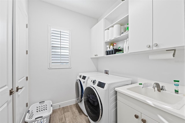 laundry area featuring cabinets, sink, washing machine and dryer, and light hardwood / wood-style flooring