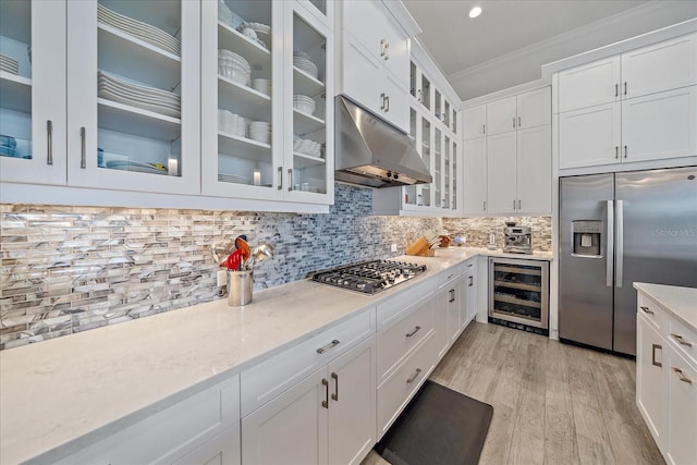 kitchen with under cabinet range hood, wine cooler, stainless steel appliances, and decorative backsplash