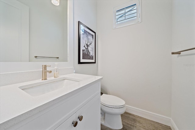 bathroom with baseboards, vanity, toilet, and wood finished floors