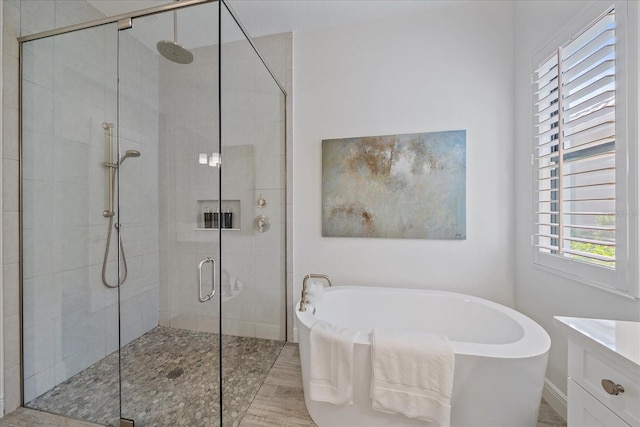 full bath with a freestanding bath, a shower stall, and vanity