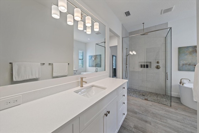 bathroom featuring a stall shower, visible vents, wood finished floors, a freestanding bath, and vanity