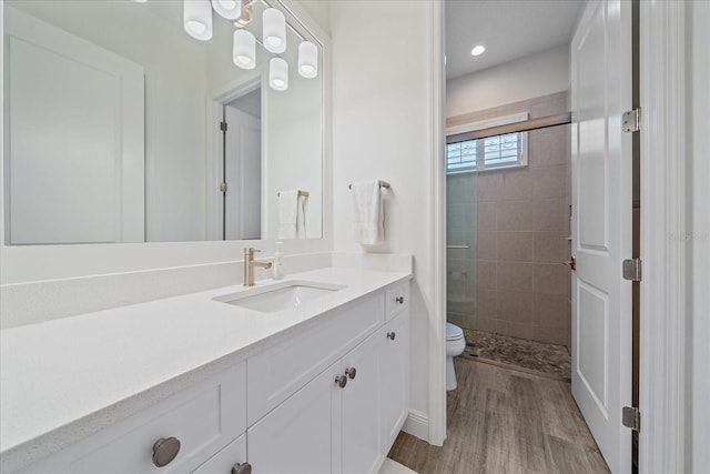 bathroom featuring toilet, a stall shower, wood finished floors, and vanity