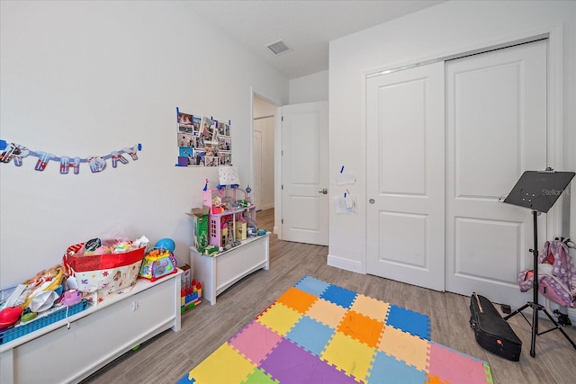 rec room featuring baseboards, visible vents, and wood finished floors