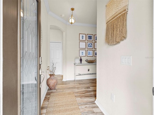 corridor with ornamental molding and light hardwood / wood-style floors