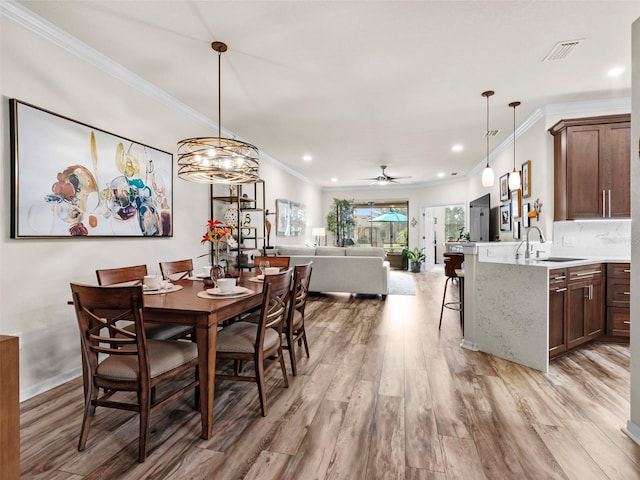 dining room with ceiling fan, sink, crown molding, and light hardwood / wood-style floors