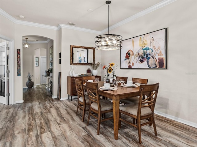 dining area featuring an inviting chandelier, crown molding, and hardwood / wood-style floors