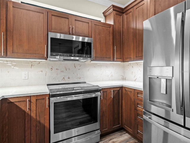 kitchen featuring decorative backsplash, light stone countertops, light hardwood / wood-style flooring, and stainless steel appliances