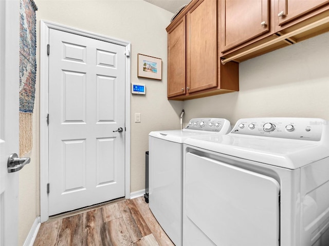 clothes washing area featuring washer and dryer, cabinets, and light hardwood / wood-style floors