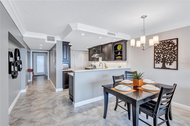 dining room with a chandelier, a textured ceiling, and ornamental molding