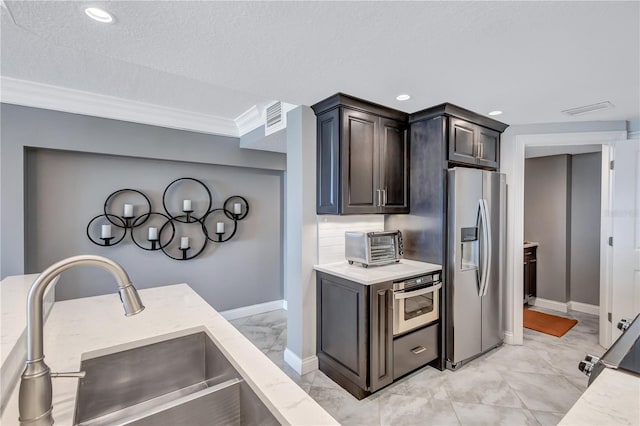 kitchen featuring appliances with stainless steel finishes, ornamental molding, dark brown cabinets, a textured ceiling, and sink