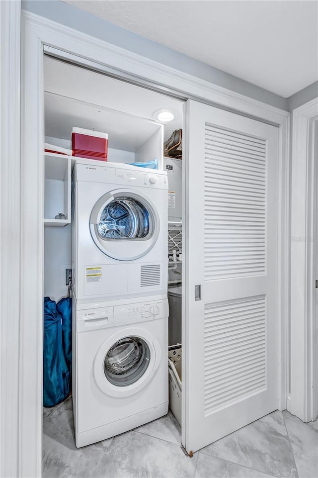 clothes washing area with stacked washing maching and dryer