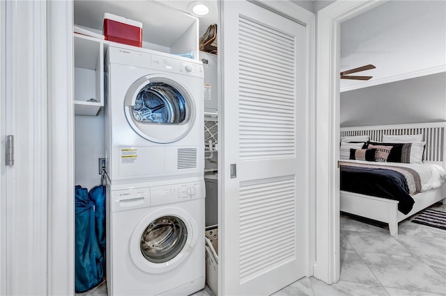 laundry area featuring ceiling fan, stacked washing maching and dryer, and crown molding