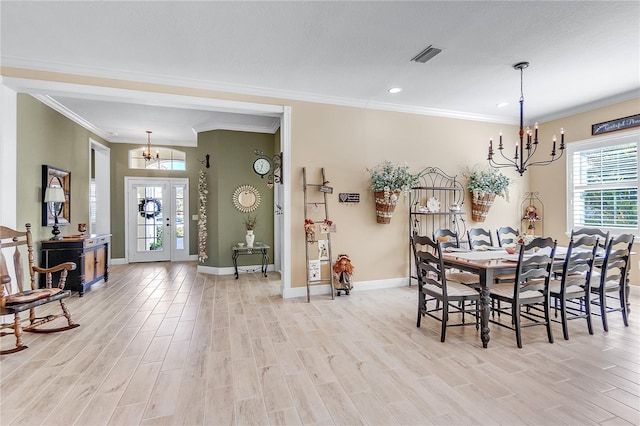 dining area featuring light wood-type flooring, an inviting chandelier, and crown molding