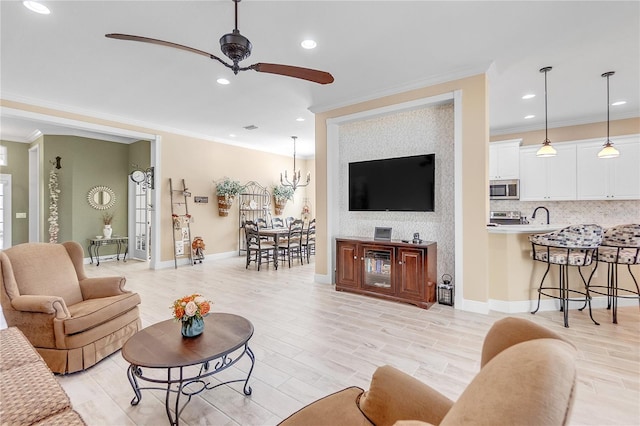 living room featuring sink, light hardwood / wood-style flooring, ceiling fan with notable chandelier, and ornamental molding