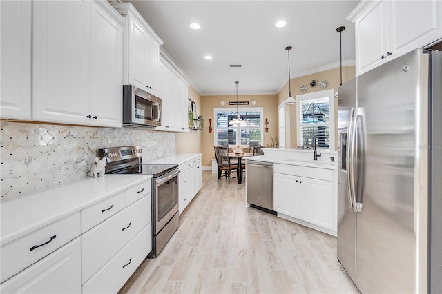 kitchen featuring sink, ornamental molding, decorative light fixtures, white cabinetry, and stainless steel appliances