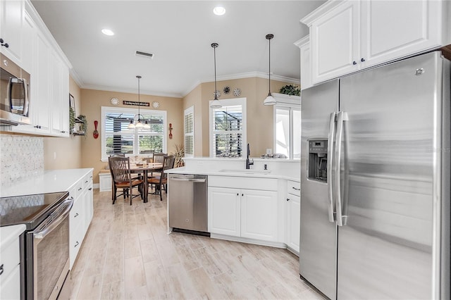 kitchen featuring sink, stainless steel appliances, pendant lighting, decorative backsplash, and white cabinets