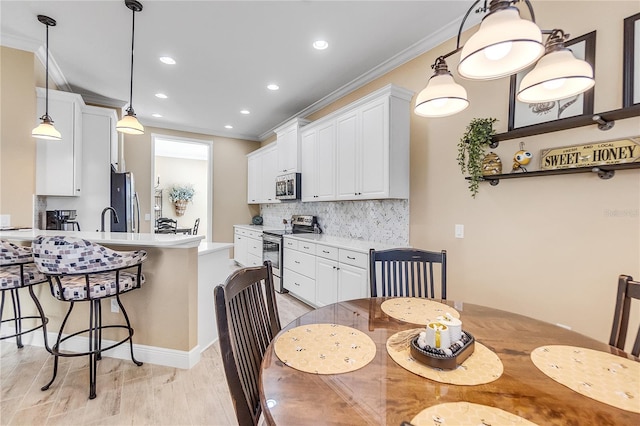 dining space with light hardwood / wood-style flooring, crown molding, and sink