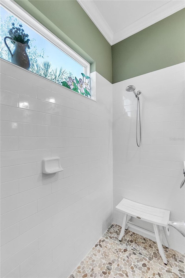 bathroom featuring a tile shower and ornamental molding