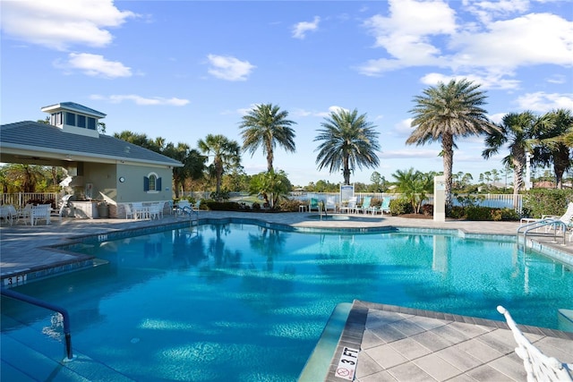 view of swimming pool featuring a patio area and exterior kitchen