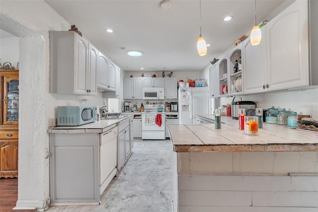 kitchen with sink, tile countertops, pendant lighting, white appliances, and white cabinets