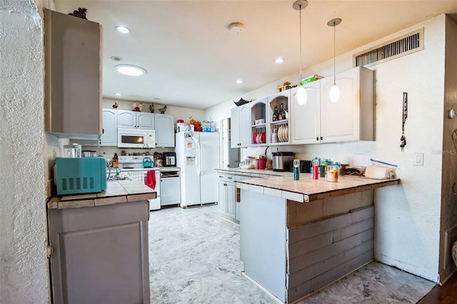 kitchen featuring kitchen peninsula, white appliances, decorative light fixtures, white cabinetry, and tile counters