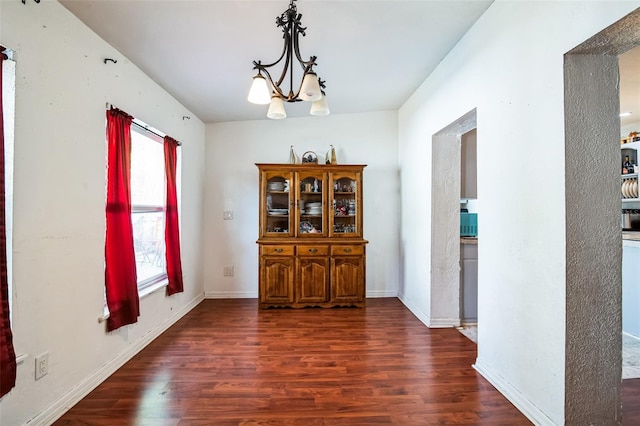 unfurnished dining area featuring plenty of natural light, dark hardwood / wood-style floors, and a notable chandelier