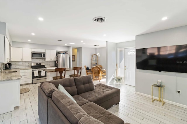 living room with light wood-type flooring and sink