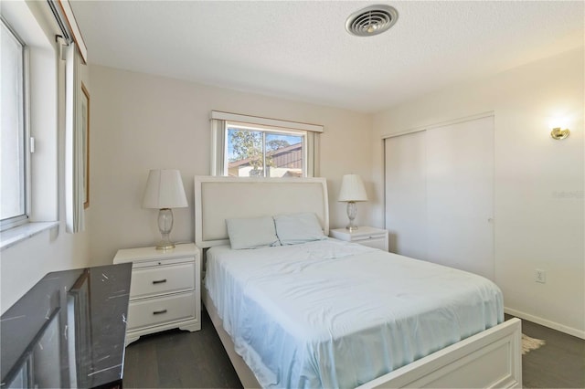 bedroom with a closet, dark hardwood / wood-style floors, and a textured ceiling