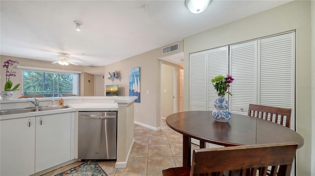 kitchen featuring sink, light tile patterned floors, stainless steel dishwasher, ceiling fan, and white cabinets