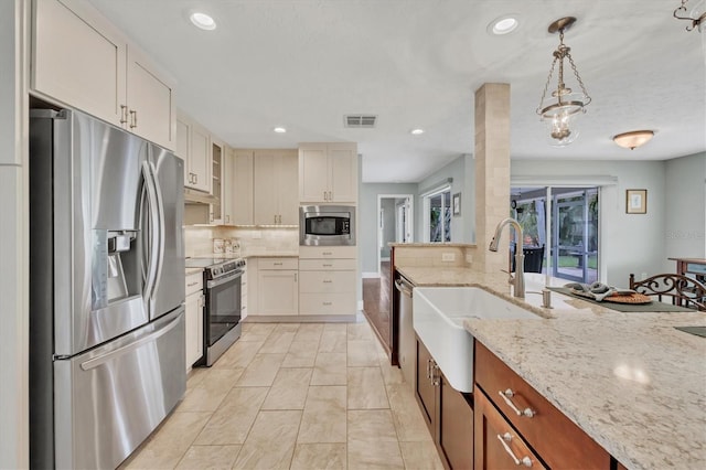 kitchen with stainless steel appliances, tasteful backsplash, decorative light fixtures, light stone countertops, and sink