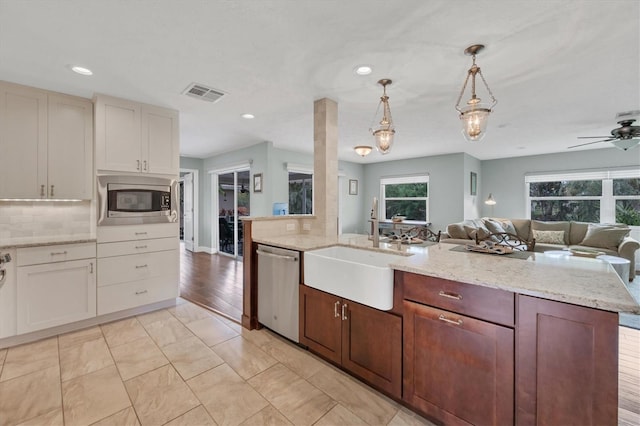 kitchen featuring pendant lighting, appliances with stainless steel finishes, sink, backsplash, and ceiling fan