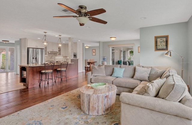 living room with ceiling fan, sink, and dark hardwood / wood-style floors