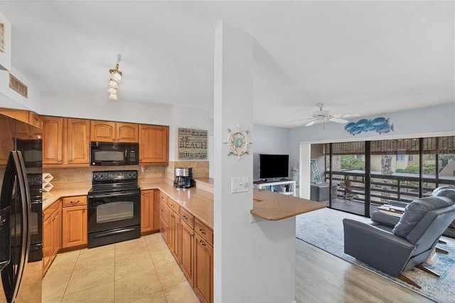 kitchen with black appliances, kitchen peninsula, light tile patterned floors, ceiling fan, and decorative backsplash