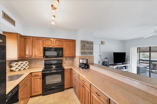 kitchen with light tile patterned floors, black appliances, tasteful backsplash, and sink