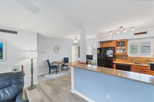 kitchen with light wood-type flooring, black appliances, tasteful backsplash, and sink