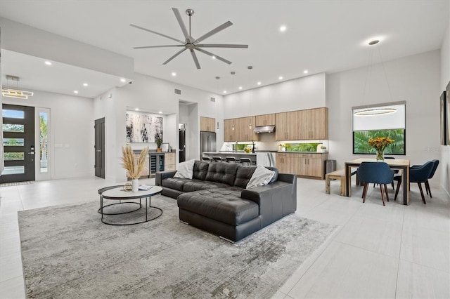 living room with ceiling fan, light tile patterned floors, and a high ceiling