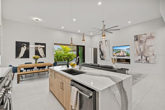 kitchen featuring a center island with sink, stainless steel appliances, decorative light fixtures, light stone countertops, and sink