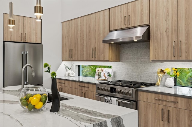 kitchen featuring appliances with stainless steel finishes, pendant lighting, tasteful backsplash, and light stone countertops